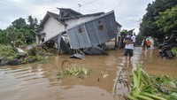 Warga melintas dekat bangunan yang roboh diterjang banjir di Perumahan Pondok Indah, Desa Jatisela, Kecamatan Gunungsari, Lombok Barat, NTB.