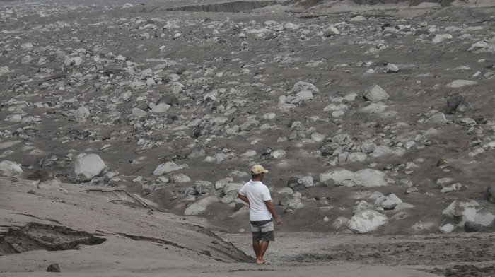 Workers move debris following an eruption of Mount Semeru, seen in the background, in Lumajang district, East Java province, Indonesia, Monday, Dec. 6, 2021. The highest volcano on Java island spewed thick columns of ash into the sky in a sudden eruption Saturday triggered by heavy rains. Villages and nearby towns were blanketed and several hamlets buried under tons of mud from volcanic debris. (AP Photo/Hendra Permana)