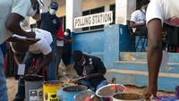 Pekerja pemilu menyiapkan drum suara di sebuah tempat pemungutan suara di Bakau, Gambia, Sabtu, 4 Desember 2021.