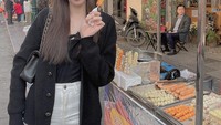 Meskipun sudah dikenal sebagai model tetapi Nguyen Thuc Thuy Tien tak gengsi jajan makanan kaki lima ini. Ia bahkan menunjuk makanan yang sedang disantapnya.  Foto: Instagram @tienng12