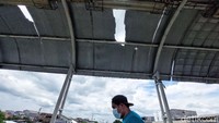 Seorang warga melintas di bawah atap JPO yang bolong. 
