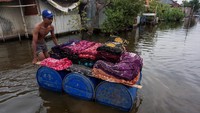 Perajin membawa kain batik menggunakan perahu rakitan saat terjadi banjir rob di Pasirsari, Pekalongan, Jawa Tengah. Selain itu penghasilan pun menurun sekitar 30-40 persen akibat banjir rob yang menggenangi kawasan tersebut sejak tiga pekan lalu.