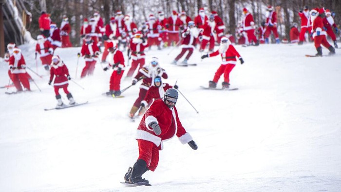 Pemain ski dan snowboarder bermain ski di lereng Minggu, 5 Desember 2021 di Resor Ski Sunday River di Newry, Maine. Keluarga Santa berkumpul untuk Hari Minggu Santa tahunan ke-21 yang mengumpulkan lebih dari $4600 untuk Dana Sungai. (Andree Kehn/Sun Journal via AP)