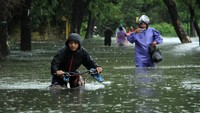 Pesepeda dan sejumlah warga menerobos banjir di Jalan Yusuf Bauty yang terendam banjir.