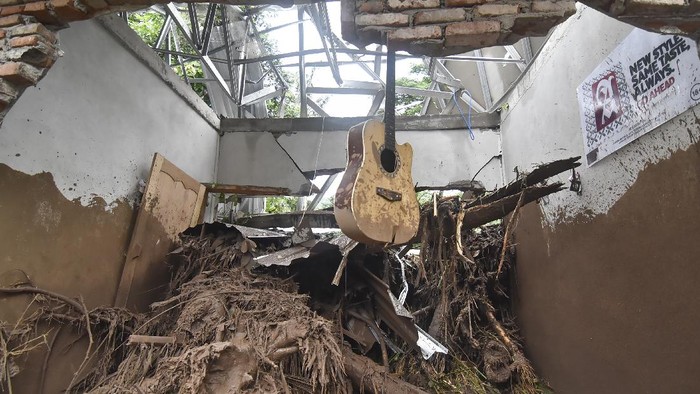 Sebuah gitar tergantung di dinding rumah yang temboknya roboh akibat diterjang banjir di Dusun Batulayar Utara, Desa Batulayar Barat, Kecamatan Batulayar, Lombok Barat, NTB, Selasa (7/12/2021). Menurut data BPBD NTB sebanyak empat korban meninggal dunia akibat banjir bandang disertai tanah longsor di Dusun Batulayar Utara dan satu korban masih hilang serta satu orang mengalami patah kaki akibat terhempas material banjir bandang. ANTARA FOTO/Ahmad Subaidi/foc.