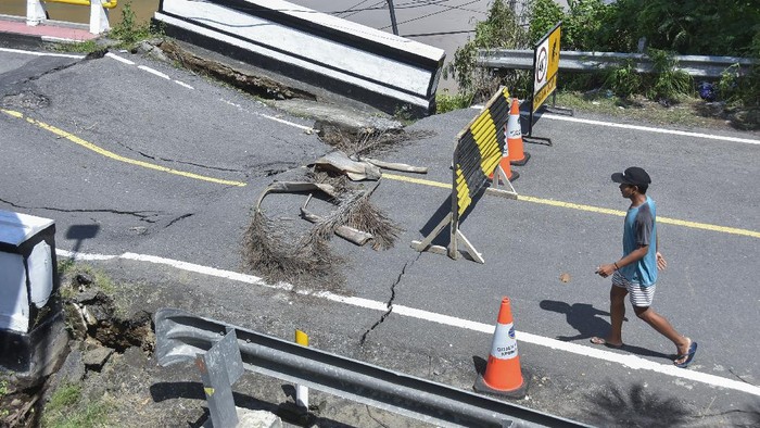 Seorang laki-laki melintas di jembatan yang rusak akibat diterjang banjir di Desa Meninting, Kecamatan Batulayar, Lombok Barat, NTB, Selasa (7/12/2021). Hujan deras dan luapan air sungai Meninting yang terjadi pada Senin (6/12) menyebabkan rusaknya jembatan Meninting yang menghubungkan antara Kota Mataram dan Kabupaten Lombok Barat. ANTARA FOTO/Ahmad Subaidi/foc.