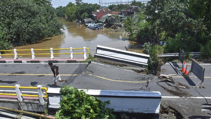 Seorang laki-laki melintas di jembatan yang rusak akibat diterjang banjir di Desa Meninting, Kecamatan Batulayar, Lombok Barat, NTB, Selasa (7/12/2021). Hujan deras dan luapan air sungai Meninting yang terjadi pada Senin (6/12) menyebabkan rusaknya jembatan Meninting yang menghubungkan antara Kota Mataram dan Kabupaten Lombok Barat. ANTARA FOTO/Ahmad Subaidi/foc.