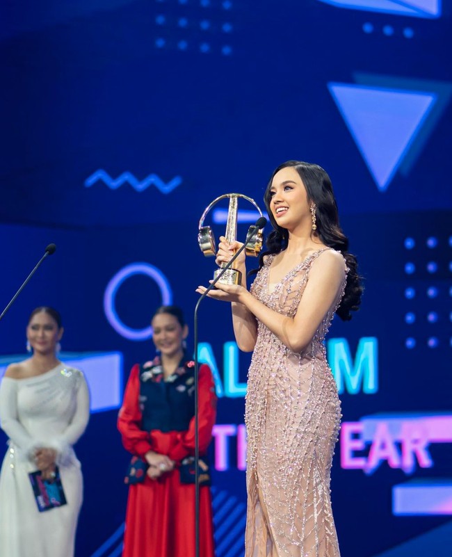 Saat menghadiri acara Indonesian Music Award, Lyodra tampil anggun dalam balutan gaun berwarna rose gold rancangan desainer Lisa Ju. Gaun yang dipenuhi dengan payet dan manik-manik itu tampak memperlihatkan lekuk tubuhnya. Foto: Instagram/lyodraofficial