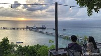 Pengunjung bersantai sambil memandang matahari tenggelam.