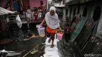 Sejumlah warga beraktivitas di tengah banjir rob yang melanda area Muara Baru, Jakarta Utara, imbas bocornya tanggul laut di kawasan itu, Selasa (7/12/2021).