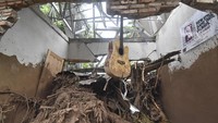 Sebuah gitar tergantung di dinding rumah yang temboknya roboh akibat diterjang banjir di Dusun Batulayar Utara. Diketahui, satu korban masih hilang serta satu orang mengalami patah kaki akibat terhempas material banjir bandang.