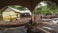 Sejumlah warga melintas dekat tumpukan kayu yang terbawa banjir. Menurut data BPBD NTB sebanyak empat korban meninggal dunia akibat banjir bandang disertai tanah longsor di Dusun Batulayar Utara.