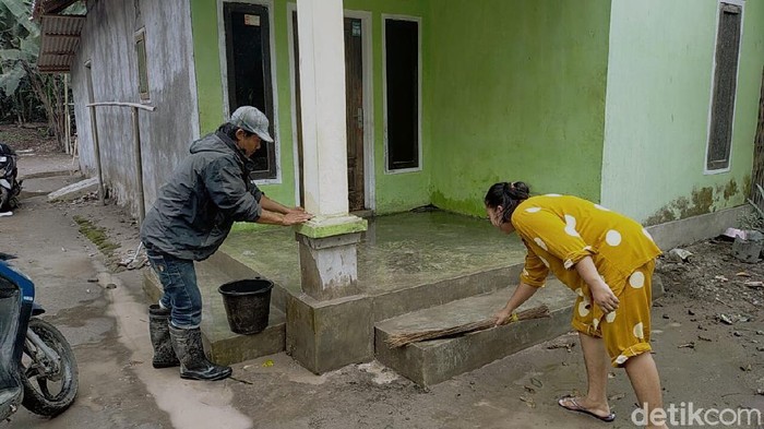 warga membersihkan rumah dari abu vulkanik semeru