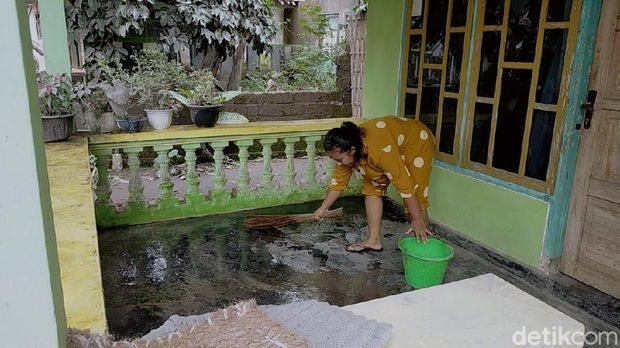warga membersihkan rumah dari abu vulkanik semeru