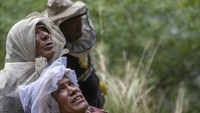 Pemburu madu Nepal menyaksikan pemimpin tim mereka Devi Bahadur Nepali, memanjat tali bambu dan memanen madu tebing di Dolakha.