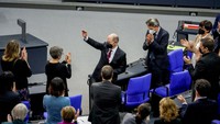 Olaf Scholz melambaikan tangan kepada anggota parlemen. Olaf Scholz merupakan politisi Partai Sosial Demokrat (SPD). Sebelumnya, ia menjadi menteri keuangan sejak 2018, Wali Kota Hamburg (2011-2018) dan wakil pemimpin SPD (2009-2019).
