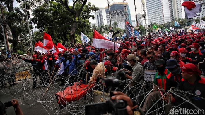 Massa buruh menarik kawat duri saat unjuk rasa di kawasa Patung Kuda, Jakarta Pusat, Rabu (8/12/2021).