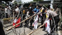 Massa buruh berupaya menjebol kawat berduri yang dipasang aparat keamanan untuk memblokade jalan menuju gedung Mahkamah Konstitusi (MK), Jalan Medan Merdeka Barat, Jakarta Pusat (Jakpus).  