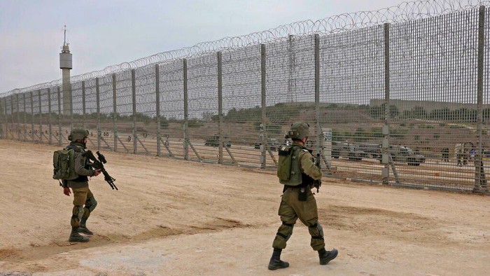 Israeli soldiers walk by the fence along the border with the Gaza Strip in southern Israel (MENAHEM KAHANA/AFP)