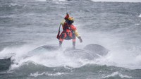 Petugas yang tampak memakai seragam oranye lengkap dengan helm pelindung itu, melawan angin kencang dan arus deras untuk mengakses mobil yang nyaris tenggelam. (AP/Jeffrey T. Barnes)