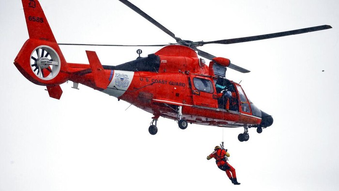 Seorang penyelam Penjaga Pantai AS, yang ditambatkan ke helikopter yang melayang, menarik tubuh dari kendaraan yang tenggelam yang terjebak dalam arus deras hanya beberapa meter dari tepi Air Terjun Niagara, Rabu, 8 Desember 2021, di Air Terjun Niagara, NY (AP Photo/ Jeffrey T.Barnes)