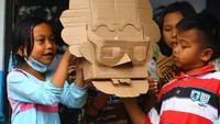 Anak-anak mencoba memainkan boneka kardus yang dibuat oleh pegiat literasi Bahana Patria Gupta di depan pengungsian bencana letusan Gunung Semeru, SDN Supiturang 4, Pronojiwo, Lumajang, Jawa Timur, Kamis (9/12/2021).