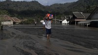 Warga membawa barang yang berhasil diamankan dari rumahnya yang tertimbun material pasir Gunung Semeru di Dusun Kamar Kajang, Candipuro, Lumajang, Jawa Timur. (ANTARA FOTO/Zabur Karuru).