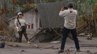 Seorang pengunjung memotret rekannya usai memberikan bantuan di kawasan terdampak letusan gunung Semeru di dusun Umbulan, Pronojiwo, Lumajang, Jawa Timur.