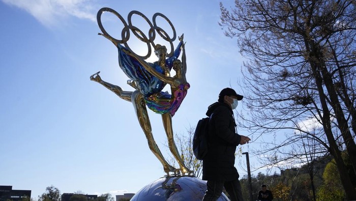 A visitor to the Shougang Park walks past the a sculpture for the Beijing Winter Olympics in Beijing, China, Tuesday, Nov. 9, 2021. China on Monday, Dec. 6, 2021, threatened to take 