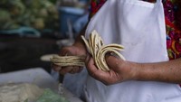 Otzoy menghitung tortilla jagung buatan tangannya di kios pasarnya di Guatemala City. Bagi jutaan keluarga Guatemala, tortilla jagung buatan tangan sangat diperlukan setiap kali makan. Versi Guatemala lebih tebal daripada kebanyakan tortilla di Meksiko, dan keduanya biasanya lebih enak daripada varietas industri kemasan yang dijual di supermarket AS. Tortilla jagung lokal buatan tangan dijual dengan harga premium di pasar jalanan Meksiko. Upah rendah sangat penting untuk mempertahankan harga tortilla yang terjangkau.