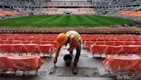 Seorang pekerja tengah memasang bangku penonton di Jakarta International Stadium (JIS), Papanggo, Jakarta Utara, Selasa (7/12/2021).