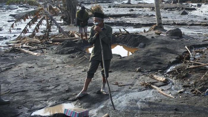 WARGA MENCARI KELUARGA YANG BELUM KETEMU Seorang warga berada di samping rumah saudarannya yang hancur dan tertimbun material Gunung Semeru di Kampung Renteng, Desa Sumberwuluh, Candipuro, Lumajang, Jawa Timur, Kamis (9/12/2021). Hari keenam penanggulangan bencana Gunung Semeru sejumlah warga terdampak awan panas guguran Gunung Semeru masih mencari keluarganya yang belum ketemu. ANTARA FOTO/Seno/hp.