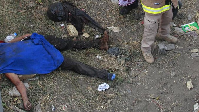 49 Migran Ilegal Tewas Kecelakaan di Meksiko The body of a man lies on the side of the road next to the overturned truck on which he was traveling near Tuxtla Gutierrez, Chiapas state, Mexico, Thursday, Dec. 9, 2021. Mexican authorities say at least 49 people were killed and dozens more injured when the truck carrying the migrants rolled over on the highway in southern Mexico. (AP Photo)