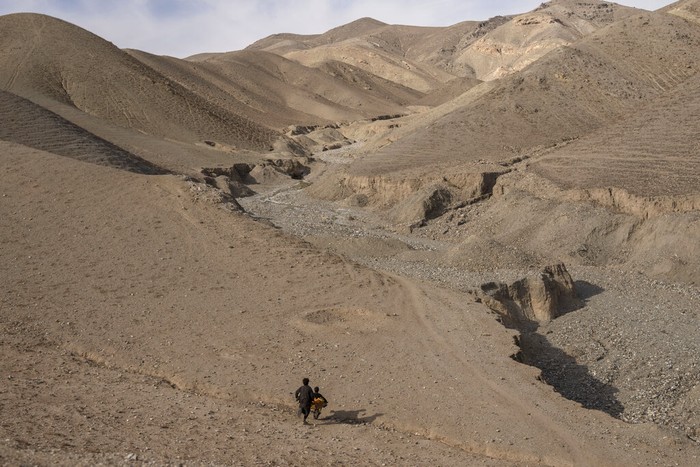 The granddaughter of Hajji Wali Jan, 66, stands at the entrance of her house in Kamar Kalagh village outside Herat, Afghanistan, Friday, Nov. 26, 2021. Afghanistan’s drought, its worst in decades, is now entering its second year, exacerbated by climate change. (AP Photo/Petros Giannakouris)