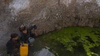 Kakak beradik ini mengisi jeriken dengan air yang tersisa di tengah pegunungan tandus di desa Kamar Kalagh, Herat, Afghanistan. Keduanya harus menempuh perjalanan hingga 3 km.