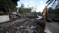 Petugas mengoperasikan ekskavator untuk membersihkan material Gunung Semeru yang menutupi jalan di Dusun Kamar Kajang, Sumberwuluh, Candipuro, Lumajang, Jawa Timur.
