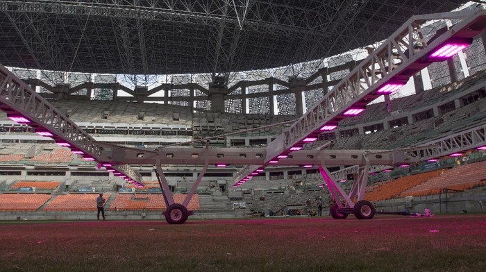 Pekerja menggunakan alat grass grow lighting untuk perawatan rumput lapangan Jakarta International Stadium (JIS) di Tanjung Priok, Jakarta, Kamis (9/12/2021). PT. Jakarta Propertindo (Jakpro) menggunakan teknologi pencahayaan ultraviolet (UV) tersebut untuk membantu pertumbuhan rumput hibrid (5 persen sintetis dan 95 persen rumput alami) lapangan stadion berkapasitas 82.000 penonton itu. ANTARA FOTO/Aditya Pradana Putra/rwa.