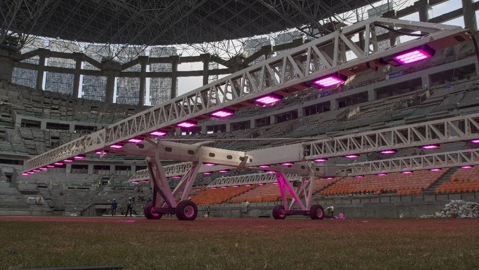 Pekerja menggunakan alat grass grow lighting untuk perawatan rumput lapangan Jakarta International Stadium (JIS) di Tanjung Priok, Jakarta, Kamis (9/12/2021). PT. Jakarta Propertindo (Jakpro) menggunakan teknologi pencahayaan ultraviolet (UV) tersebut untuk membantu pertumbuhan rumput hibrid (5 persen sintetis dan 95 persen rumput alami) lapangan stadion berkapasitas 82.000 penonton itu. ANTARA FOTO/Aditya Pradana Putra/rwa.