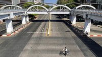 Seseorang mengendarai sepeda di jalan kosong di pusat kota Yangon, Myanmar.