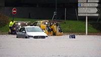 Kendaraan derek berusaha mengevakuasi mobil yang terjebak banjir.