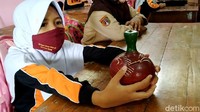 Salah satu murid SD kelas 3 SD, Stafira Aqila Marsudi (8) membawa sebuah celengan yang terbuat dari tanah liat. Celengan merupakan istilah umum untuk menyebut kotak penyimpanan uang koin, meski kotak itu bukan lagi berbentuk celeng (babi liar).
