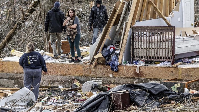 Chelsea Emmons holds on to a cat, Marinda, that belongs to her mother, Kim Goforth, Saturday, Dec. 11, 2021, in Bremen, Ky, while searching Goforth's home that was destroyed by a tornado late Friday evening. Emmons found the cat hiding in a dresser drawer. (Greg Eans/The Messenger-Inquirer via AP)