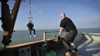Ini pemimpin mereka, Liam Bates, Pangeran Kerajaan Sealand. Dia sedang turun dari kerajaan dengan menggunakan kerekan. (BEN STANSALL/AFP)
