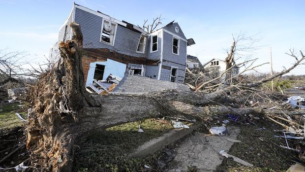 An overturned tree sits in front of a tornado damaged home in Mayfield, Ky., on Saturday, Dec. 11, 2021. Tornadoes and severe weather caused catastrophic damage across multiple states Friday, killing dozens of people overnight. (AP Photo/Mark Humphrey)