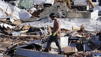 Warga berjalan di rertuntuhan rumah hancur disapu tornado.