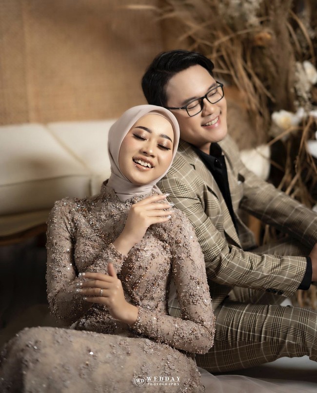 Pada sesi foto prewedding lainnya, Hemas dan Danang kompak mengenakan busana bernuansa earth tone. Hemas mengenakan hijab segi empat polos warna nude yang dililit rapi ke belakang, agar memperlihatkan detail payet pada dress berkerah shanghai. Momen tersebut diabadikan oleh fotografer Wedday Photography. Foto: Dok.Instagram @hemasnura.