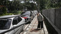 Seorang pejalan kaki melintas di trotoar yang terdapat kabel menjuntai di Jalan TMP Taruna, Kota Tangerang, Banten, Senin (13/12/2021).
