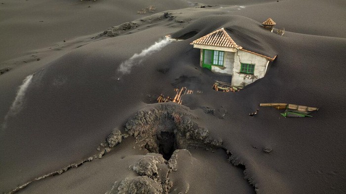 FILE - Sebuah celah terlihat di sebelah rumah yang tertutup abu di pulau Canary La Palma, Spanyol, 1 Desember 2021. Letusan gunung berapi di Kepulauan Canary Spanyol tidak menunjukkan tanda-tanda akan berakhir setelah 85 hari. Ini menjadi pulau dengan letusan terpanjang di La Palma yang tercatat pada hari Minggu, 12 Desember. (AP Photo/Emilio Morenatti, file)