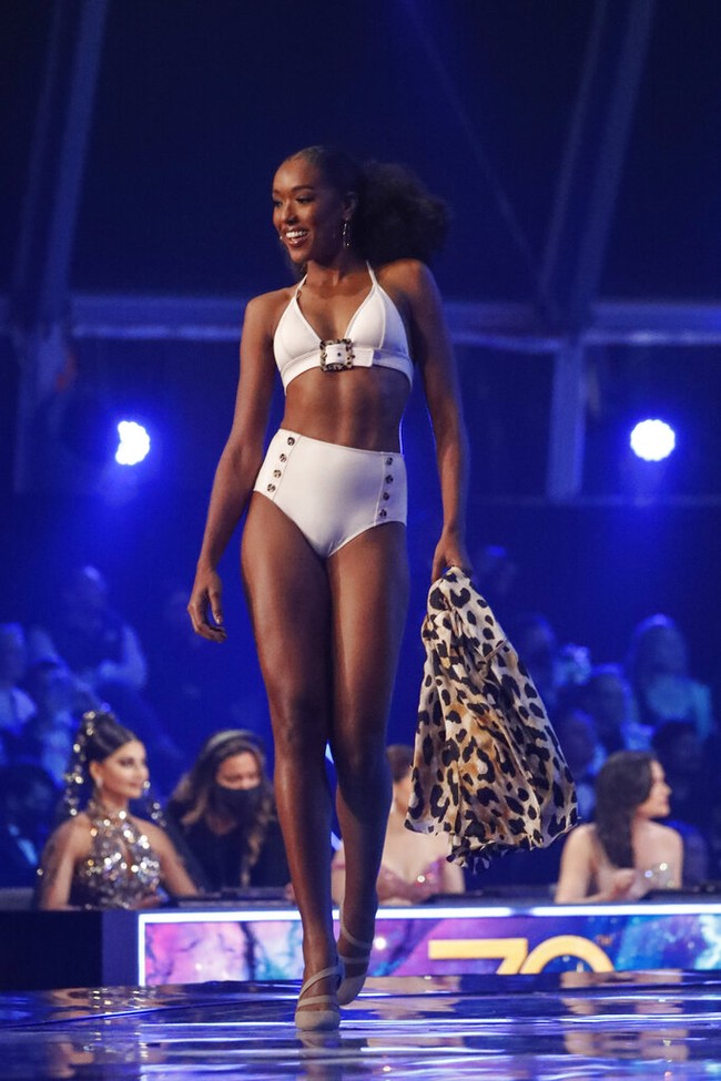 Inilah penampilan Thessaly Zimmerman dari Aruba. Ia muncul balutan balutan swimsuit putih yang terdiri atasan beraksen sabuk dan celana yang dihiasi kancing. (Foto: AP/Ariel Schalit)