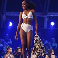 Inilah penampilan Thessaly Zimmerman dari Aruba. Ia muncul balutan balutan swimsuit putih yang terdiri atasan beraksen sabuk dan celana yang dihiasi kancing. (Foto: AP/Ariel Schalit)